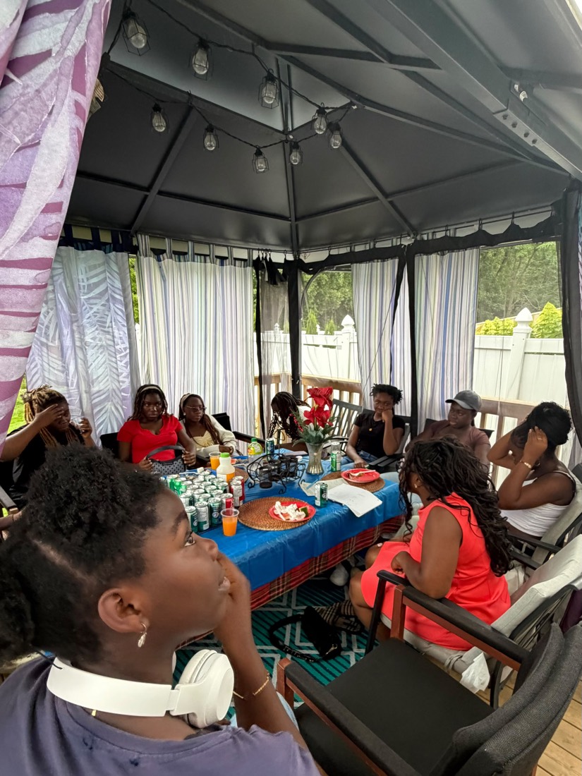Youth and mentors seated around the table under the garden gazebo sharing a meal and conversation